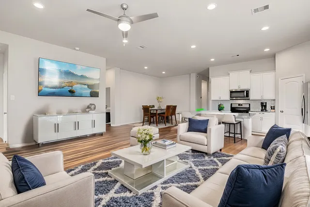 a living room with furniture kitchen view and a chandelier