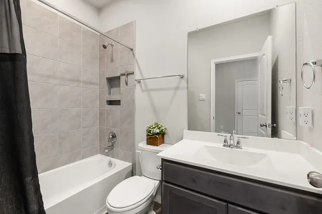 a bathroom with a sink a toilet a mirror a bathtub and shower