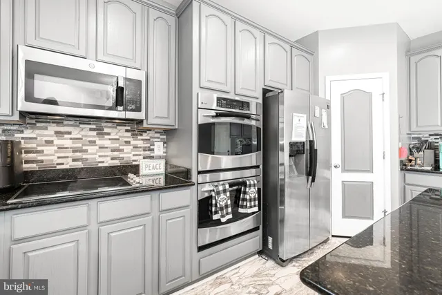 a kitchen with stainless steel appliances granite countertop a refrigerator a sink dishwasher and white cabinets with wooden floor