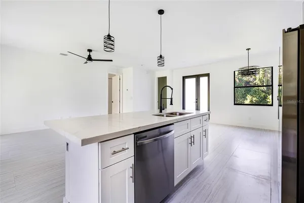 a kitchen with stainless steel appliances granite countertop a sink a center island a stove and a wooden floor