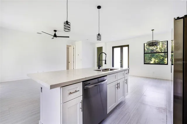 a kitchen with stainless steel appliances granite countertop a sink a center island a stove and a wooden floor