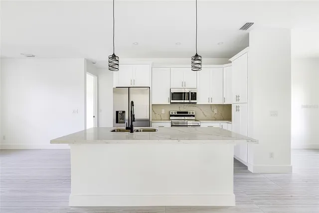 a kitchen with stainless steel appliances a sink a microwave a center island and cabinets