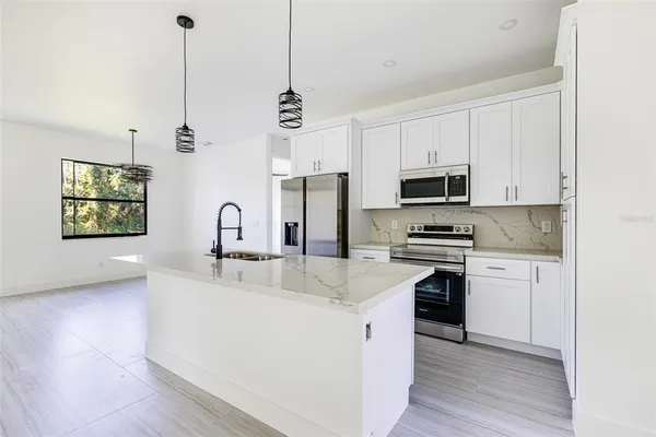 a kitchen with stainless steel appliances granite countertop a sink a stove a refrigerator cabinets and a wooden floor