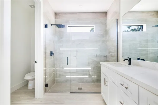 a bathroom with a sink a toilet and shower