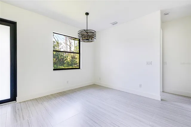 a view of an empty room with window and wooden floor