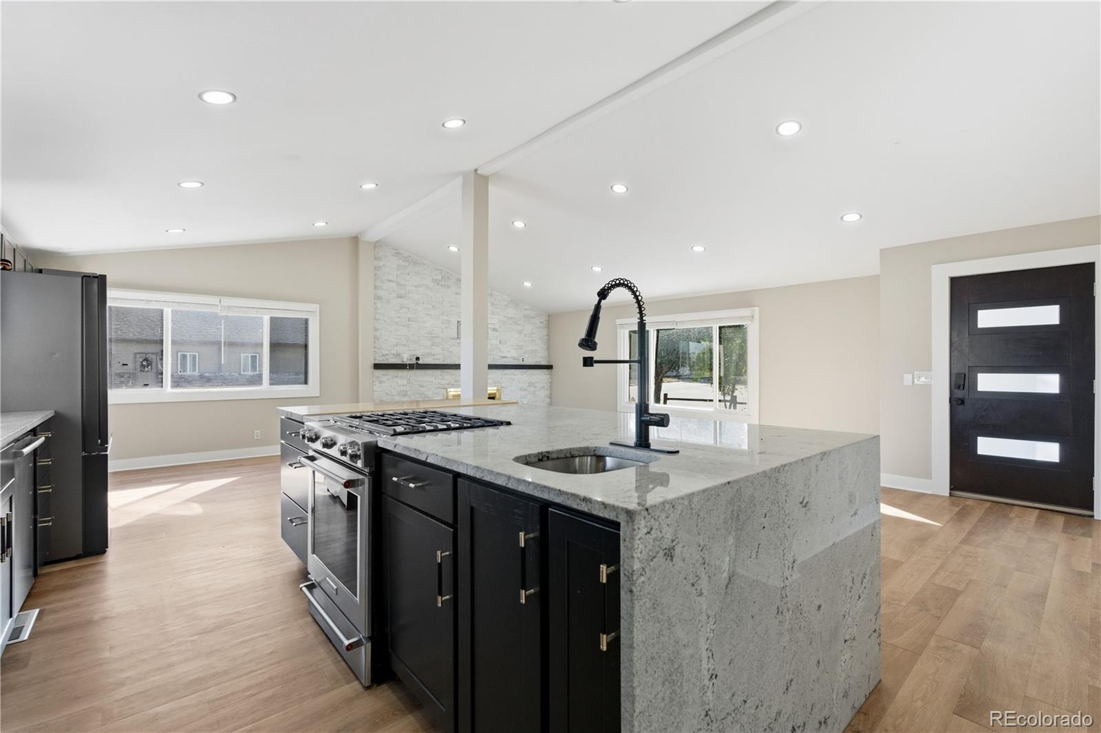 a kitchen with stainless steel appliances granite countertop a sink a stove and a wooden floors