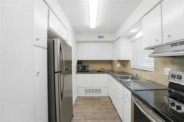 a kitchen with a sink a refrigerator and cabinets