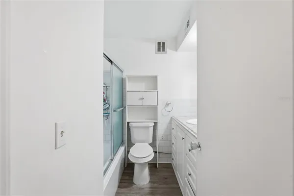 a bathroom with a granite countertop toilet a sink and a window