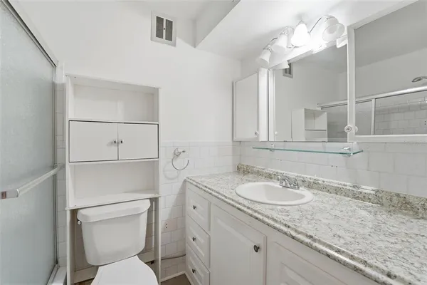 a bathroom with a granite countertop sink a toilet and mirror
