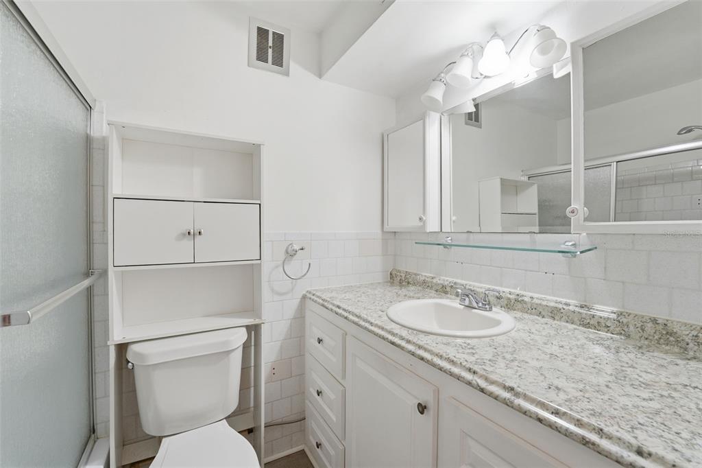 3900 Roxane Boulevard, Unit 10A Sarasota, FL 34235 - Photo 21 of 30 a bathroom with a granite countertop sink a toilet and mirror