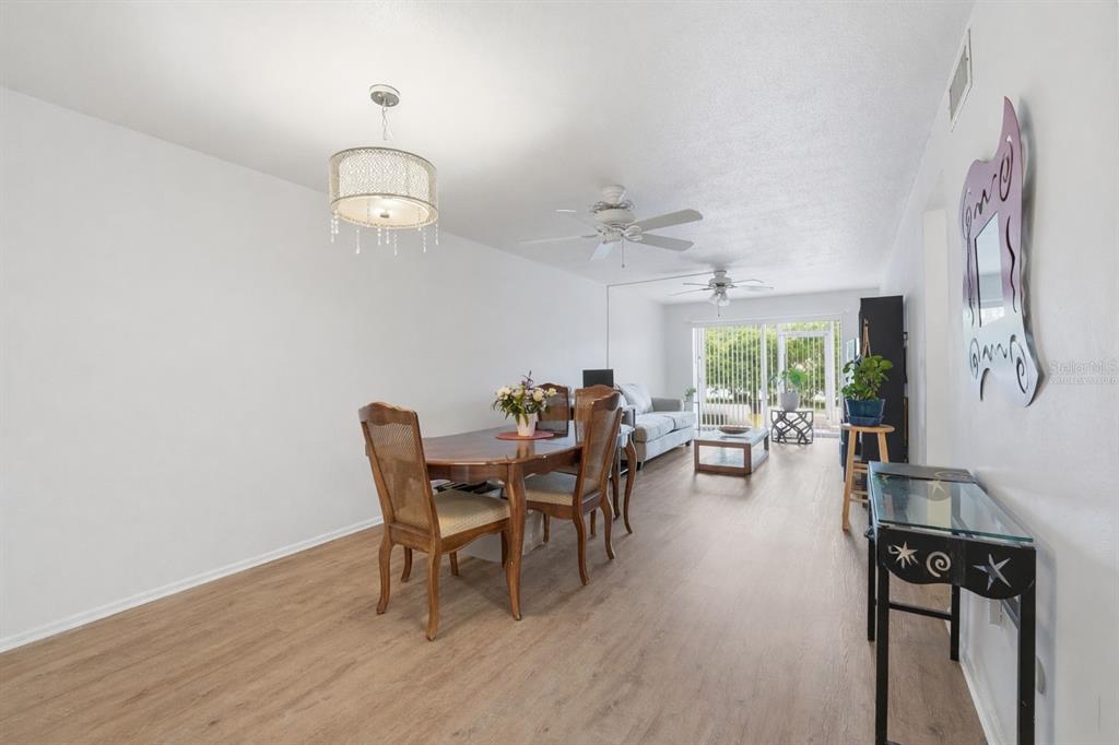 3900 Roxane Boulevard, Unit 10A Sarasota, FL 34235 - Photo 6 of 30 a dining room with wooden floor a chandelier a wooden table and chairs