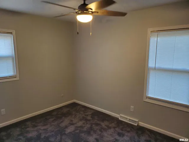 an empty room with a window and chandelier fan