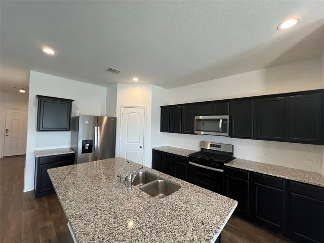 a kitchen with stainless steel appliances kitchen island granite countertop a stove refrigerator and microwave