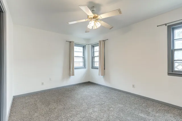 an empty room with windows and fan