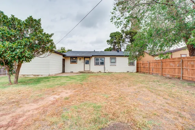 a view of a house with a backyard and a tree