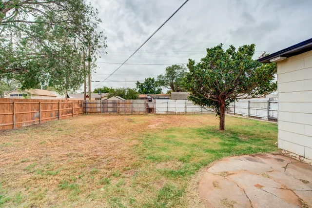 a view of yard with tree and wooden fence