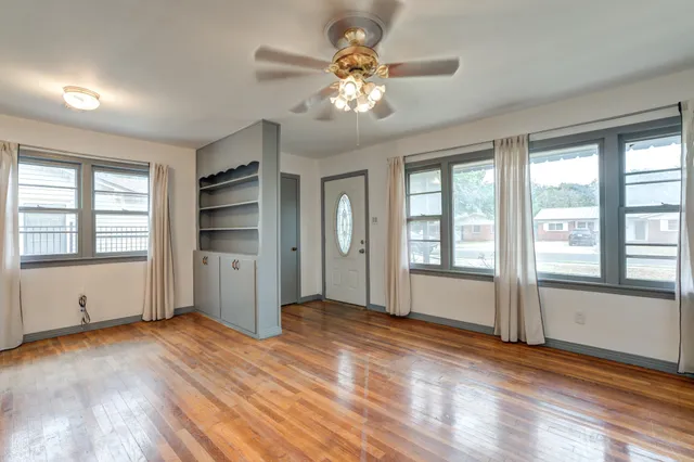 a view of an empty room with window and wooden floor