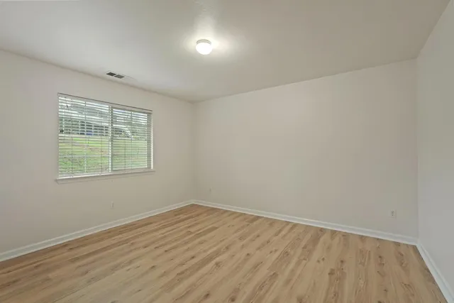 an empty room with wooden floor and windows