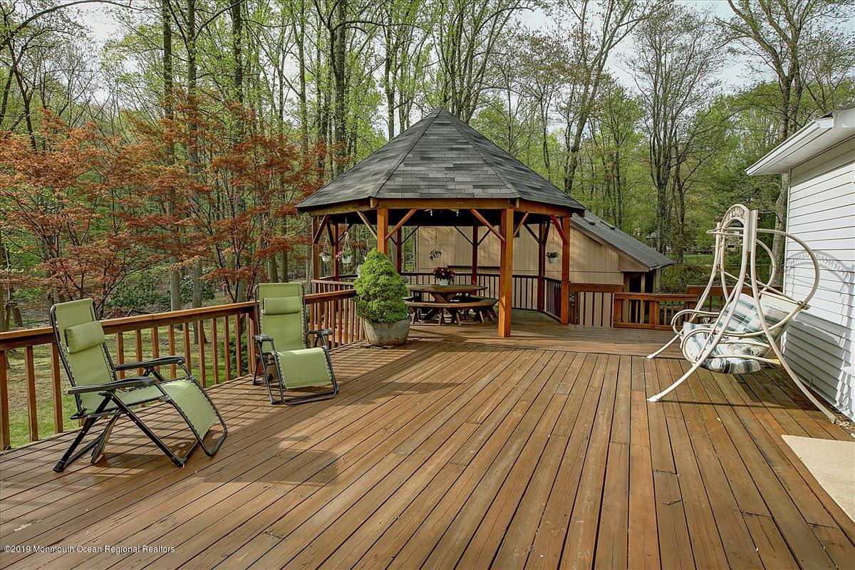 111 Reids Hill Road Morganville, NJ 07751 - Photo 29 of 39 a view of a roof deck with table and chairs under an umbrella with wooden floor