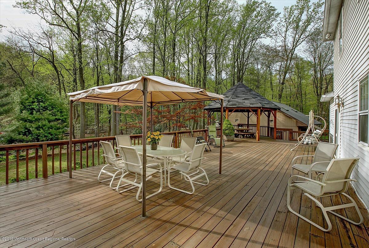 111 Reids Hill Road Morganville, NJ 07751 - Photo 30 of 39 a view of a patio with table and chairs under an umbrella with wooden floor