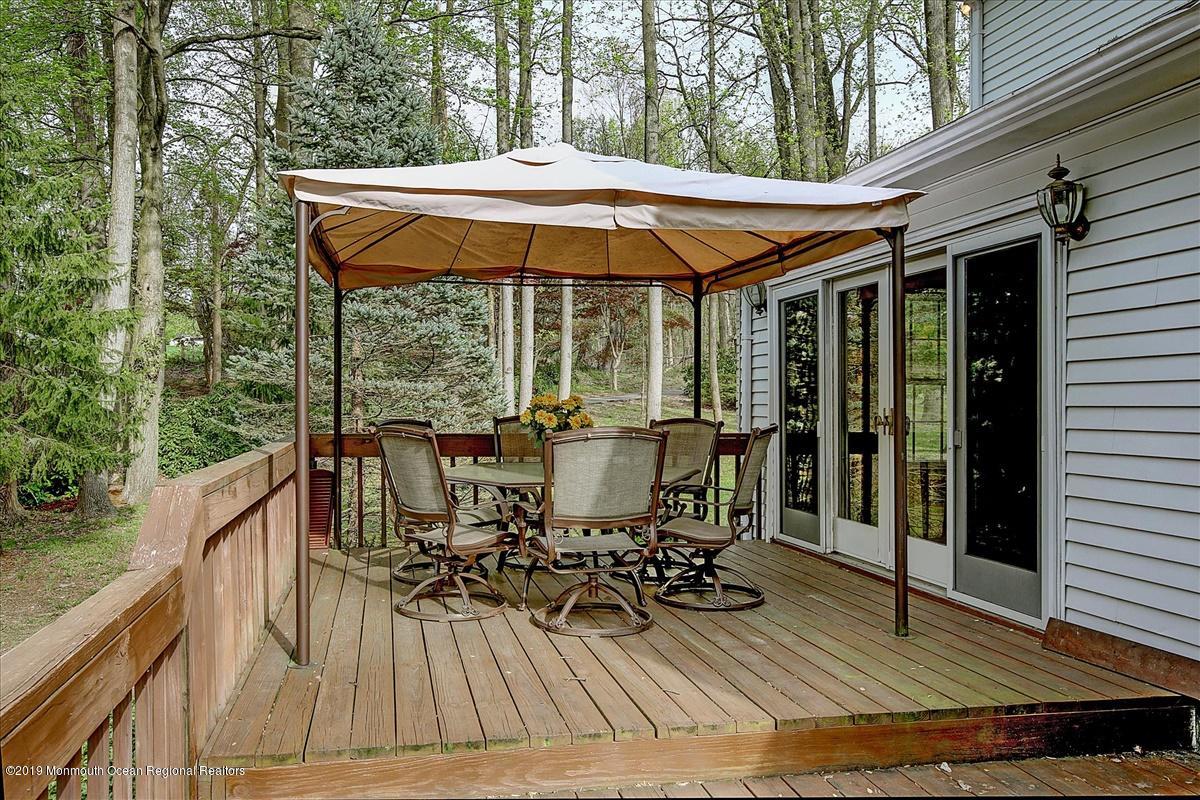111 Reids Hill Road Morganville, NJ 07751 - Photo 34 of 39 a view of deck with table and chairs under an umbrella with wooden floor