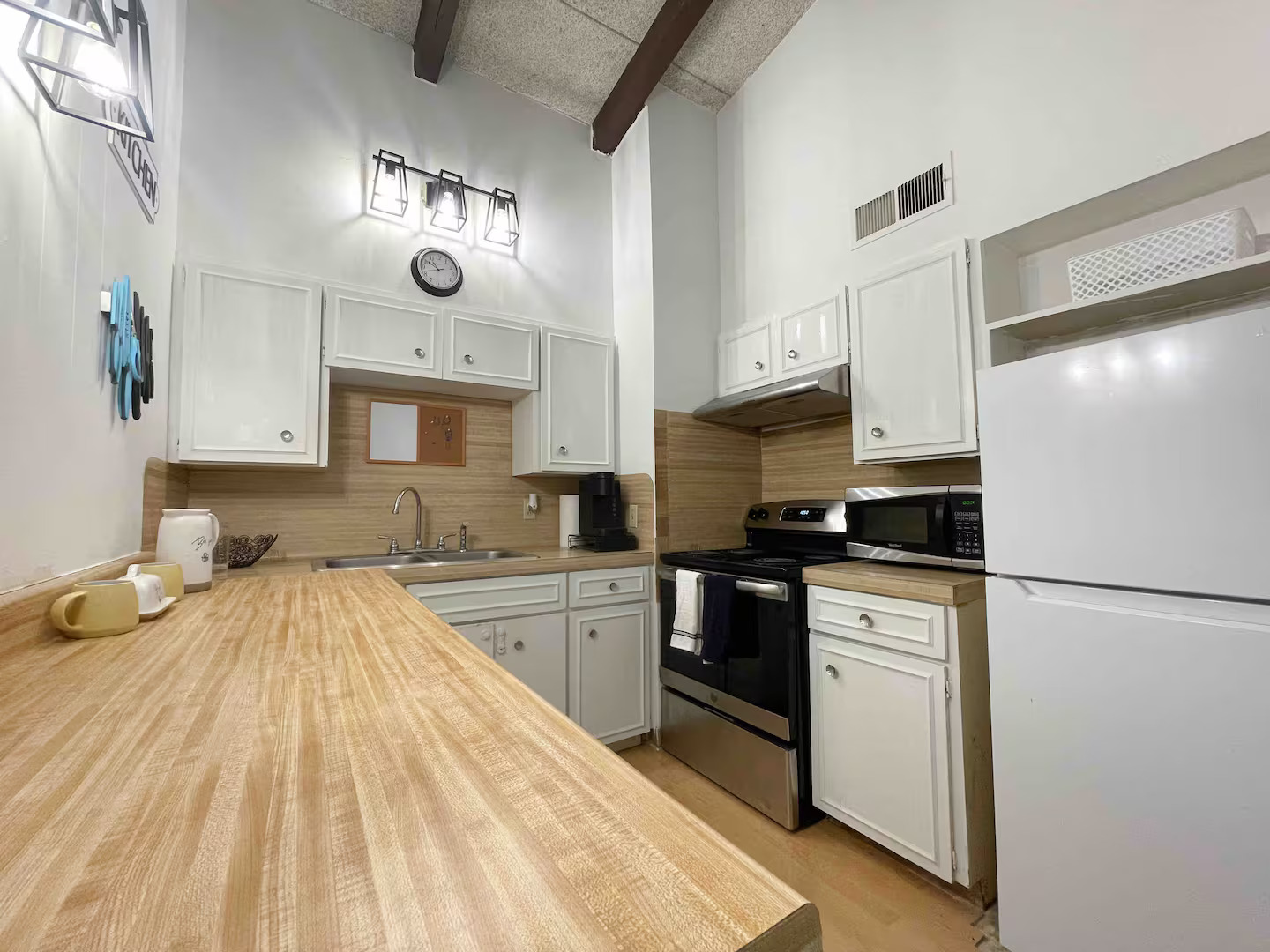 2404 Longview Street, Unit 204 Austin, TX 78705 - Photo 1 of 9 Kitchen with stainless steel appliances, white cabinetry, open shelves, tasteful backsplash, and lofted ceiling