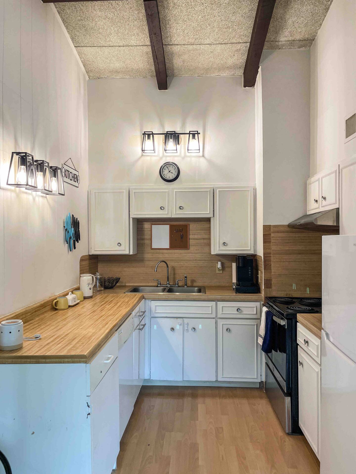 2404 Longview Street, Unit 204 Austin, TX 78705 - Photo 2 of 9 Kitchen featuring white cabinetry, light countertops, white appliances, light wood finished floors, and beam ceiling