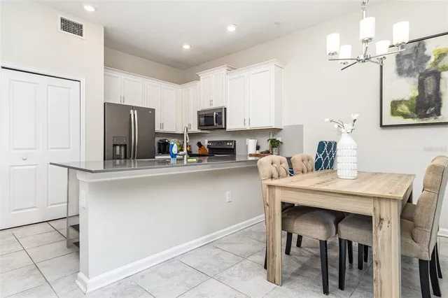 a kitchen with a refrigerator a stove a sink and chairs