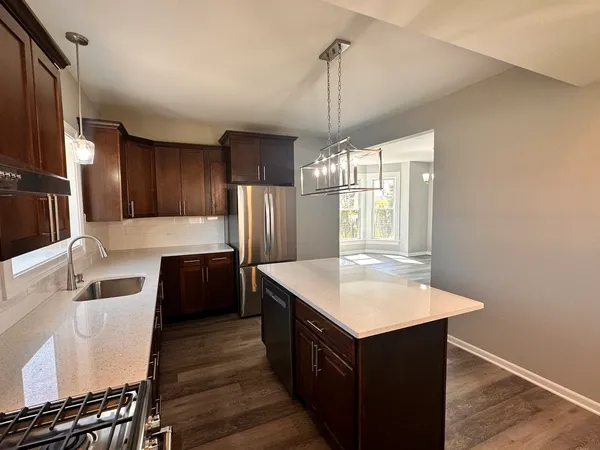 a kitchen with kitchen island granite countertop a sink and refrigerator