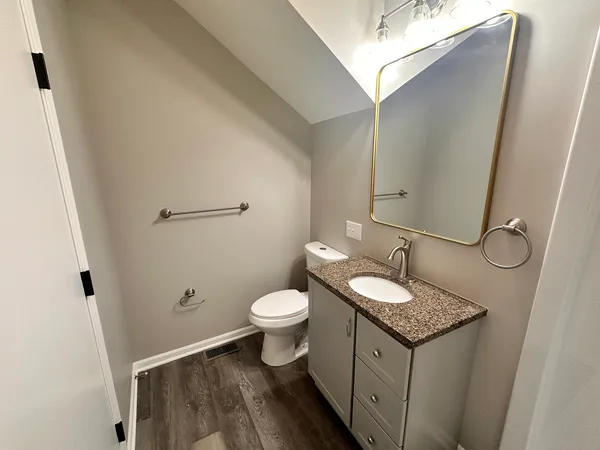 a bathroom with a granite countertop sink toilet and a mirror
