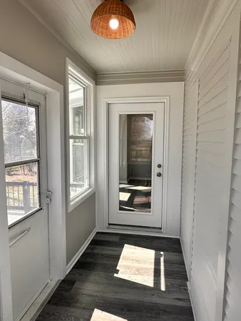 an entryway in a hall with wooden floor and a window