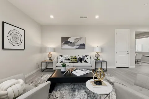 a living room with furniture couches and a dining table with wooden floor