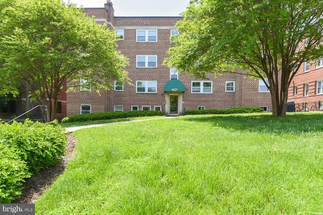 a brick house with a big yard and large trees