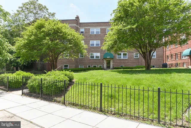 a view of a brick house with a big yard and large trees