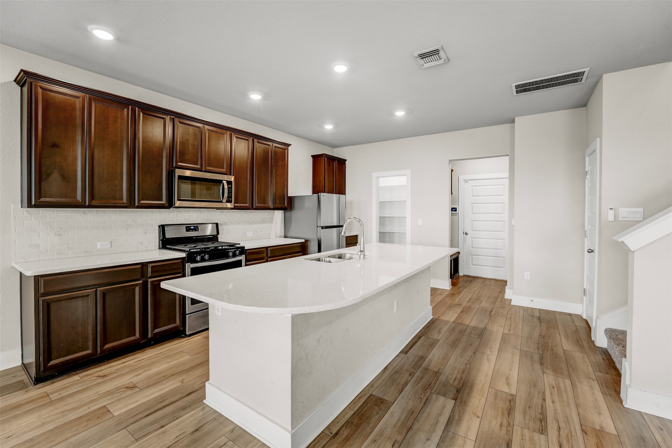 7509 Grand Linden Way, Unit 87 Austin, TX 78744 - Photo 5 of 30 a large kitchen with stainless steel appliances sink a stove and wooden floor