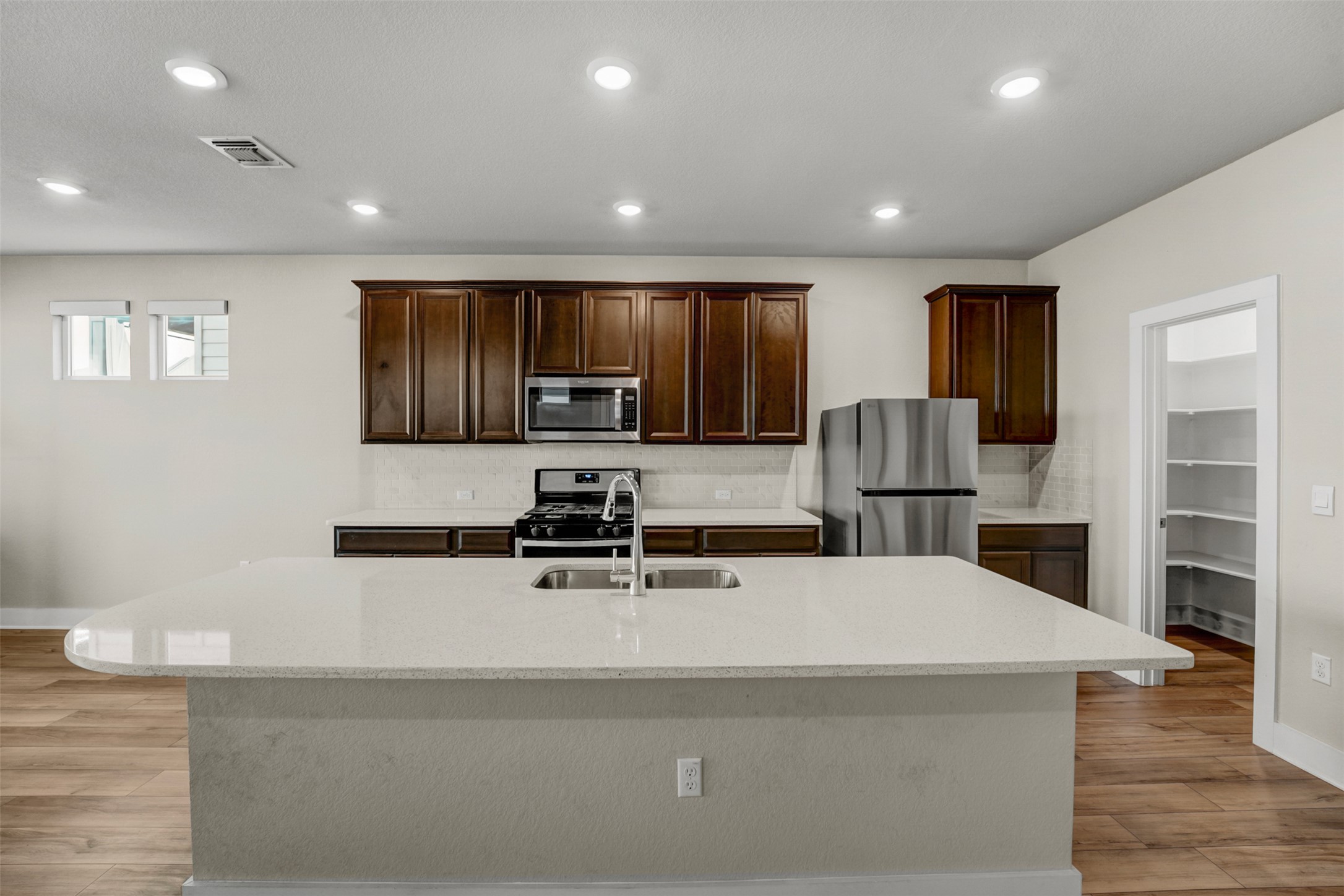 7509 Grand Linden Way, Unit 87 Austin, TX 78744 - Photo 6 of 30 a large kitchen with stainless steel appliances a large counter top a stove and a refrigerator with wooden floor