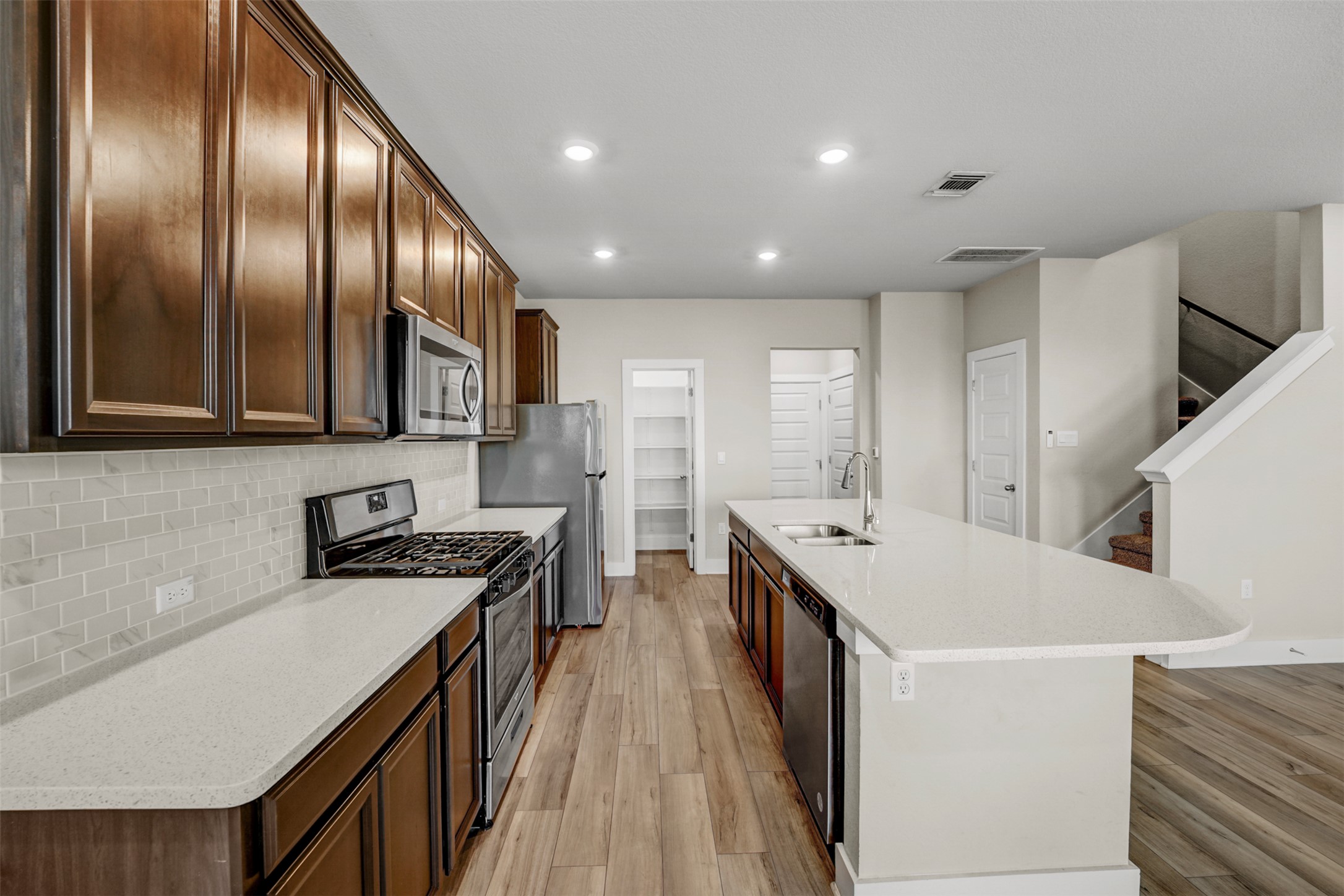 7509 Grand Linden Way, Unit 87 Austin, TX 78744 - Photo 7 of 30 a kitchen with stainless steel appliances a stove a refrigerator a sink and dishwasher with wooden floor