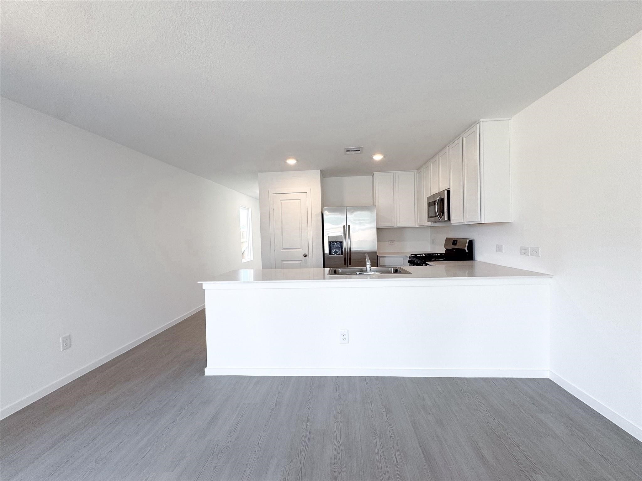 12431 Wild Strawberry Road Houston, TX 77038 - Photo 3 of 18 a large white kitchen with wooden floors