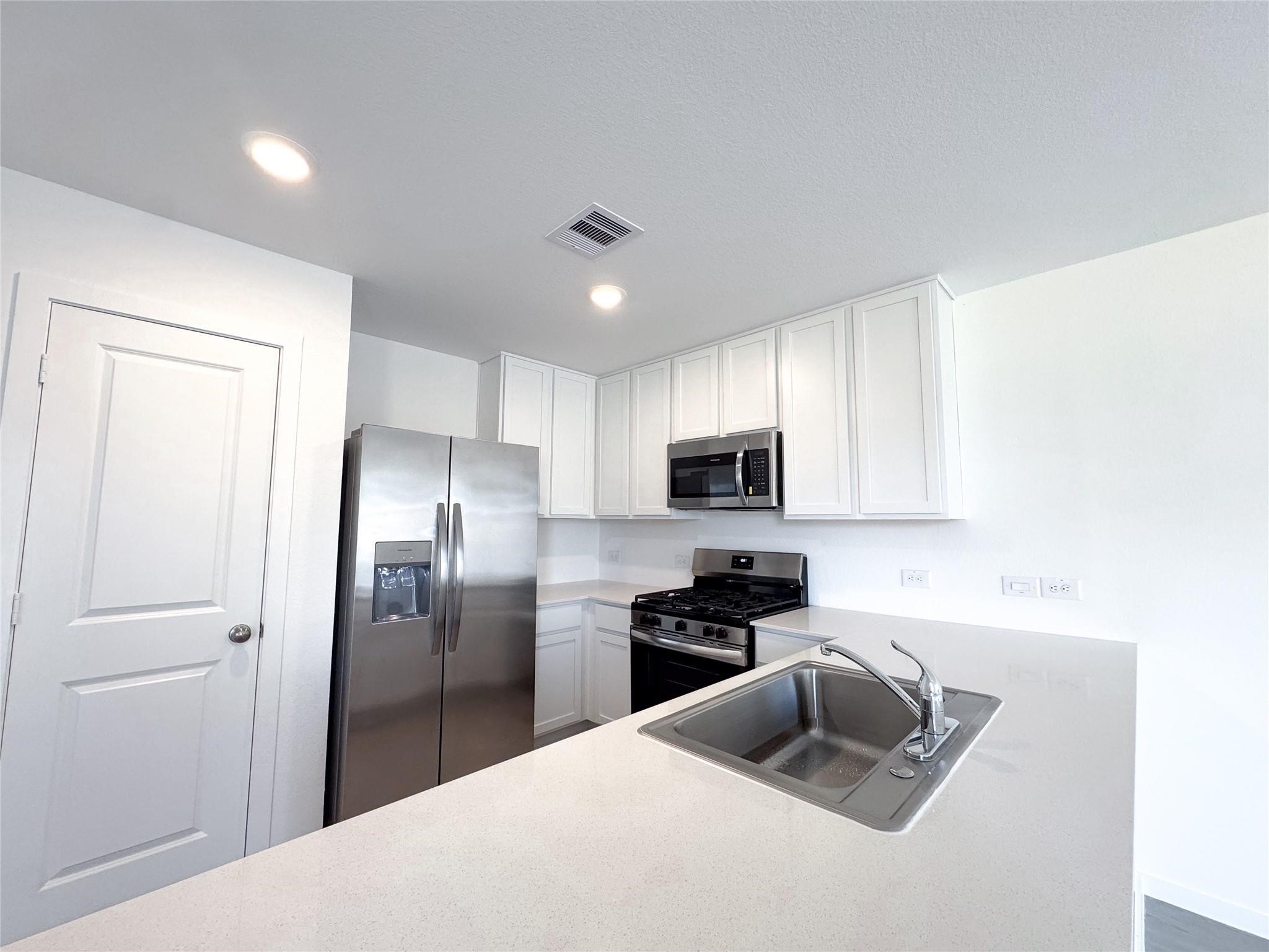 12431 Wild Strawberry Road Houston, TX 77038 - Photo 4 of 18 a kitchen with kitchen island granite countertop a refrigerator a sink a stove a microwave and wooden cabinets
