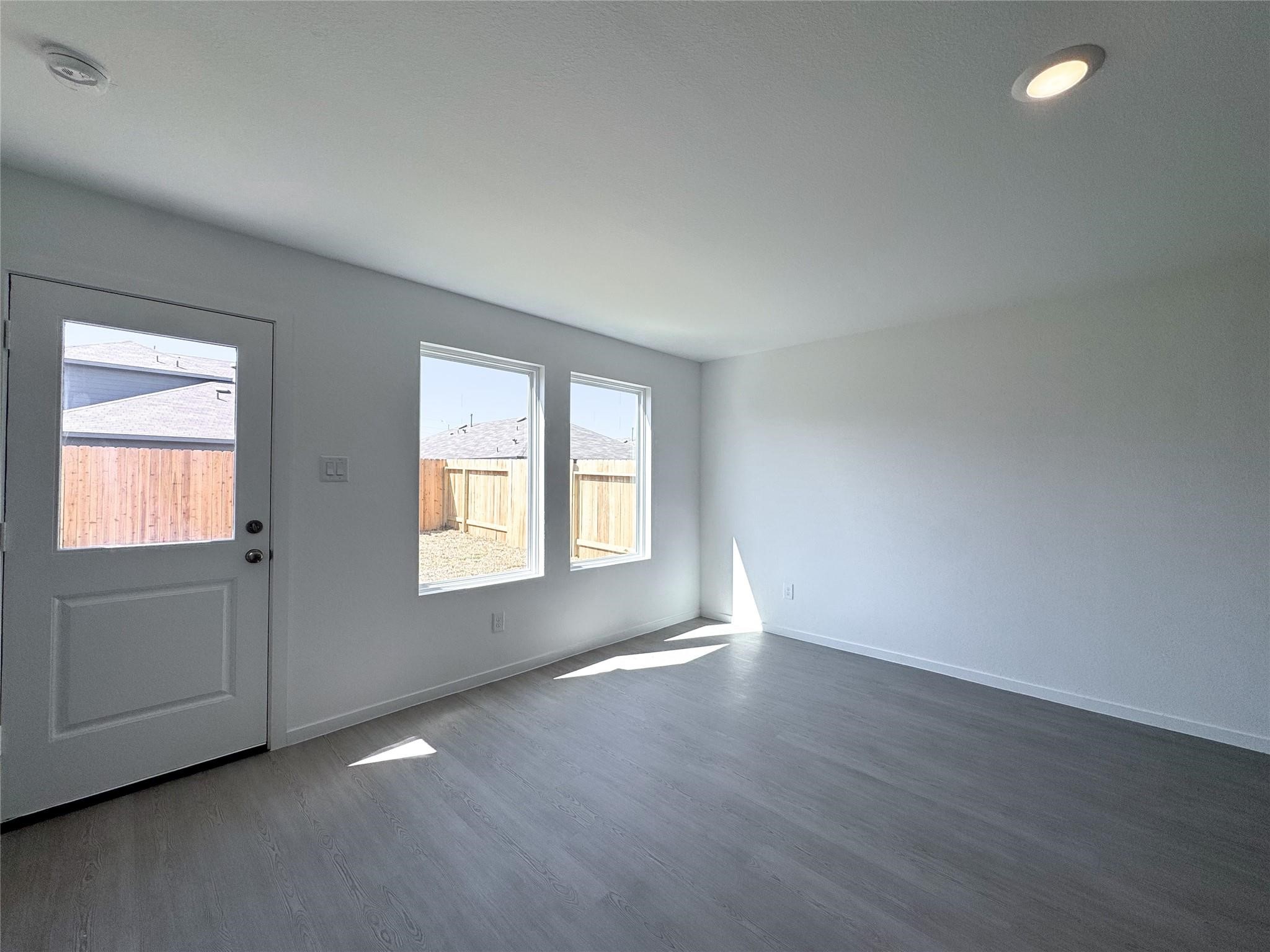 12431 Wild Strawberry Road Houston, TX 77038 - Photo 9 of 18 an empty room with wooden floor and windows
