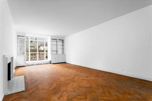 a view of an empty room with a fireplace and a window
