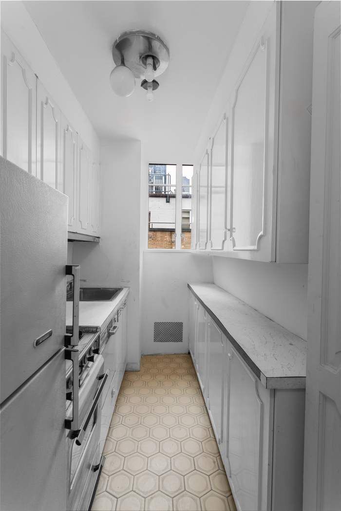 24 West 55th Street, Unit 10E Manhattan, NY 10019 - Photo 6 of 12 a kitchen with granite countertop a sink and cabinets