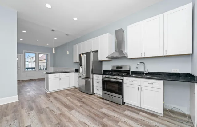 a kitchen with stainless steel appliances granite countertop a stove a sink and white cabinets