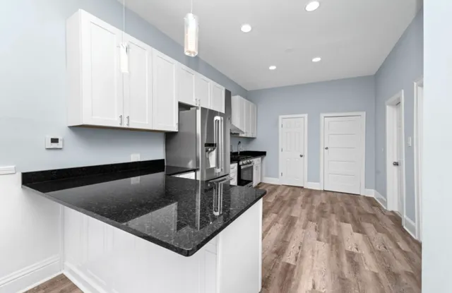 a kitchen with stainless steel appliances granite countertop a sink a microwave and a refrigerator