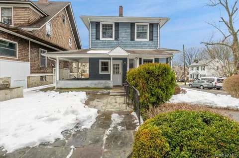 a front view of a house with a yard and potted plants