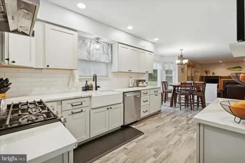 a kitchen with stainless steel appliances kitchen island granite countertop a refrigerator oven a sink dishwasher and white cabinets with wooden floor