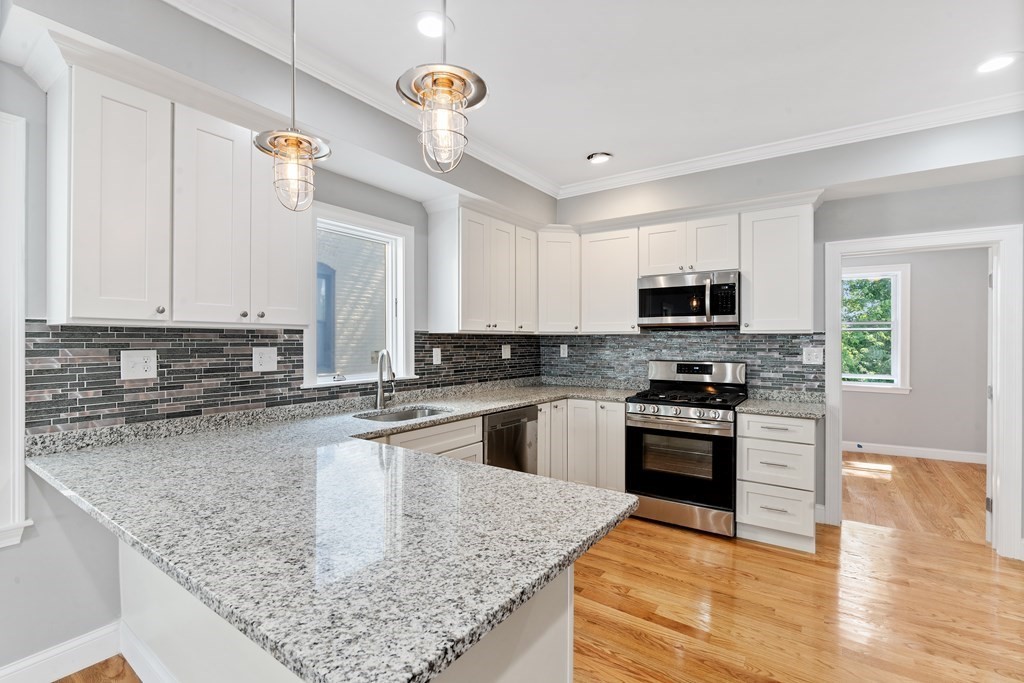 9 Wales Street, Unit 2 Boston, MA 02124 - Photo 10 of 15 a kitchen with stainless steel appliances granite countertop a sink stove microwave and refrigerator