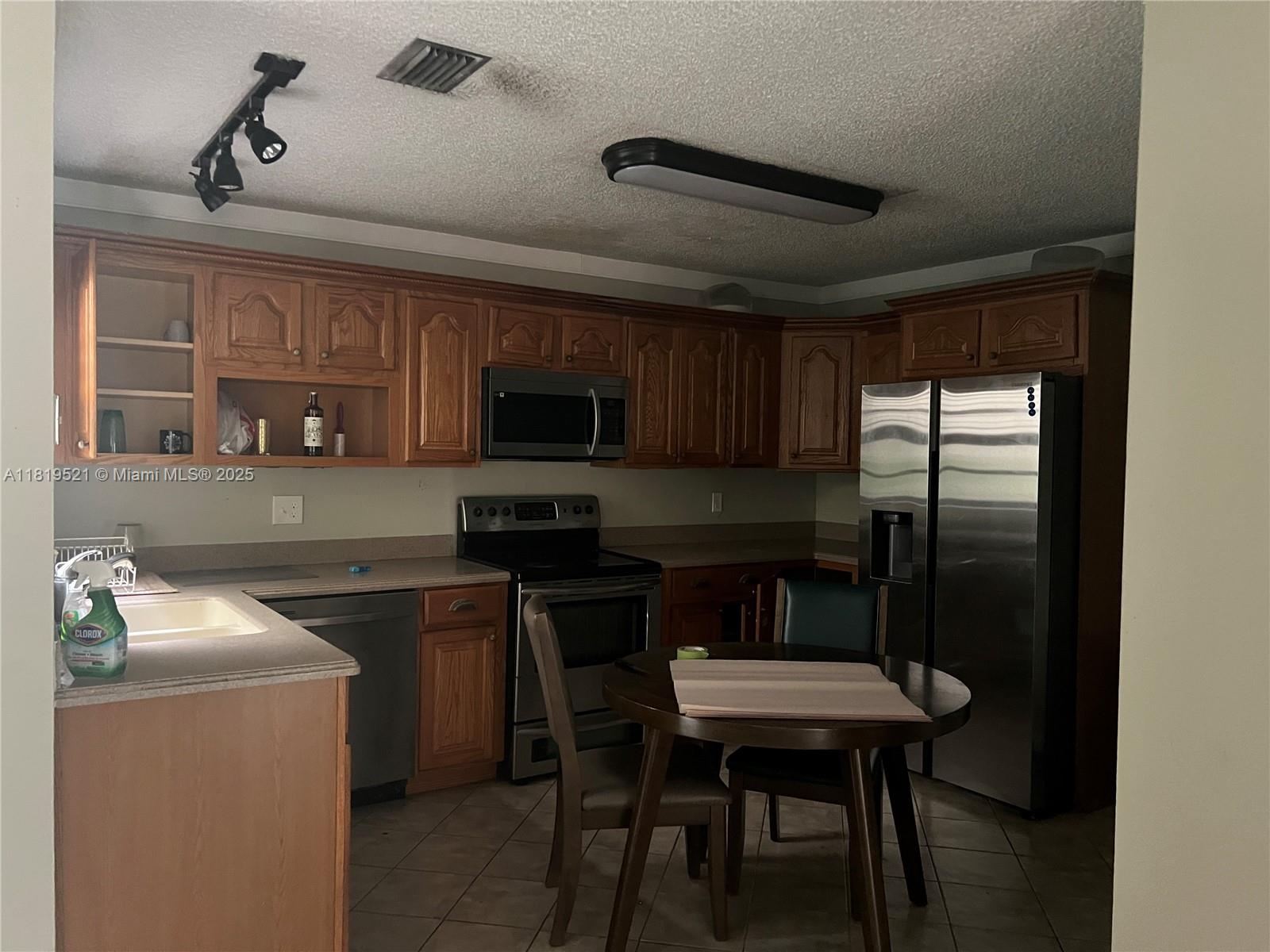 6885 Northwest 169th Street, Unit 66D Hialeah, FL 33015 - Photo 2 of 3 a kitchen with a table chairs refrigerator and microwave