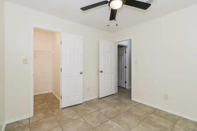 an empty room with a window and ceiling fan