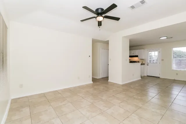 a view of a livingroom with a ceiling fan and kitchen space